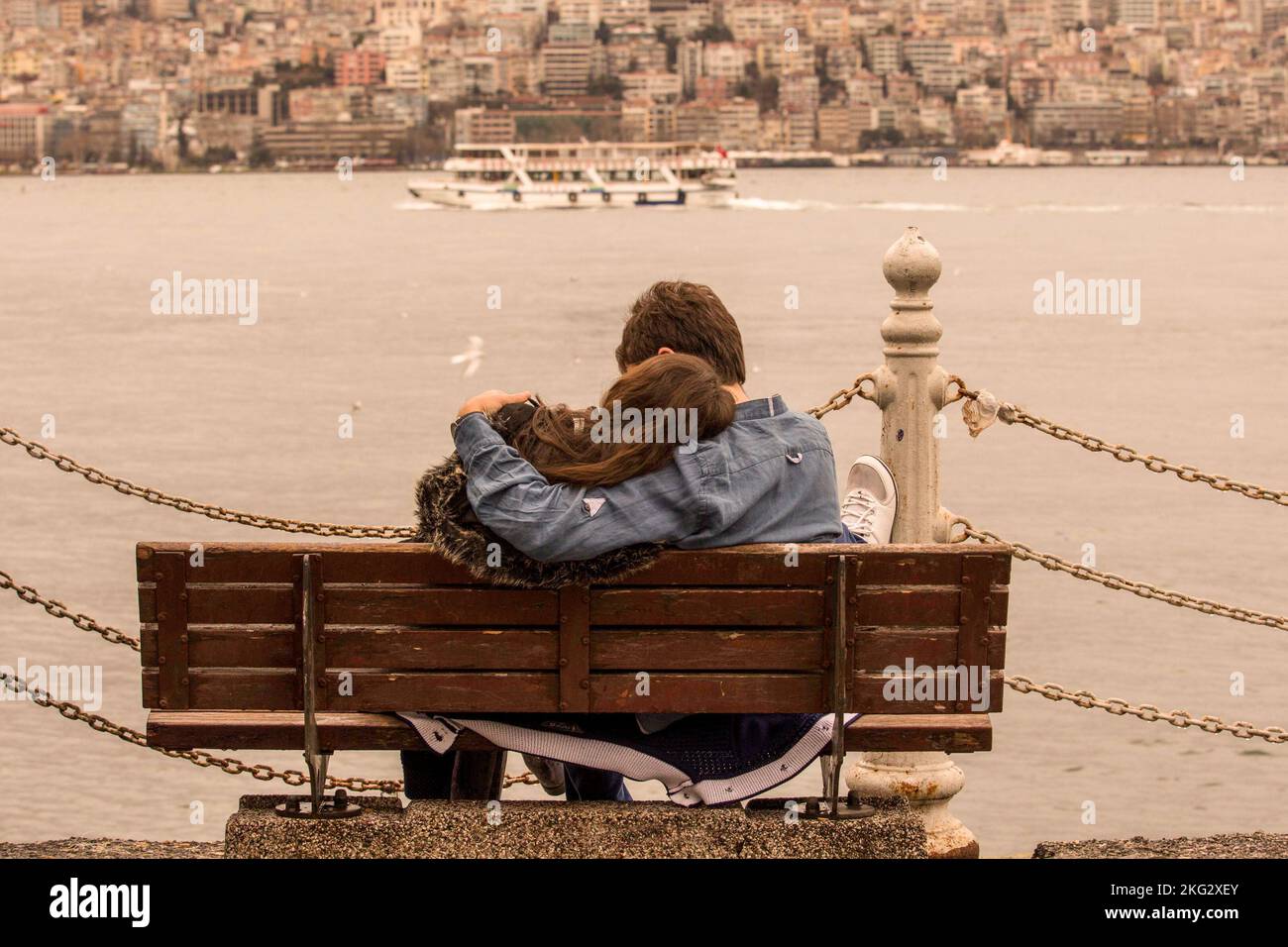 Un charmant couple embrassant et assis sur un banc près de la rivière à Uskudar, Turquie Banque D'Images