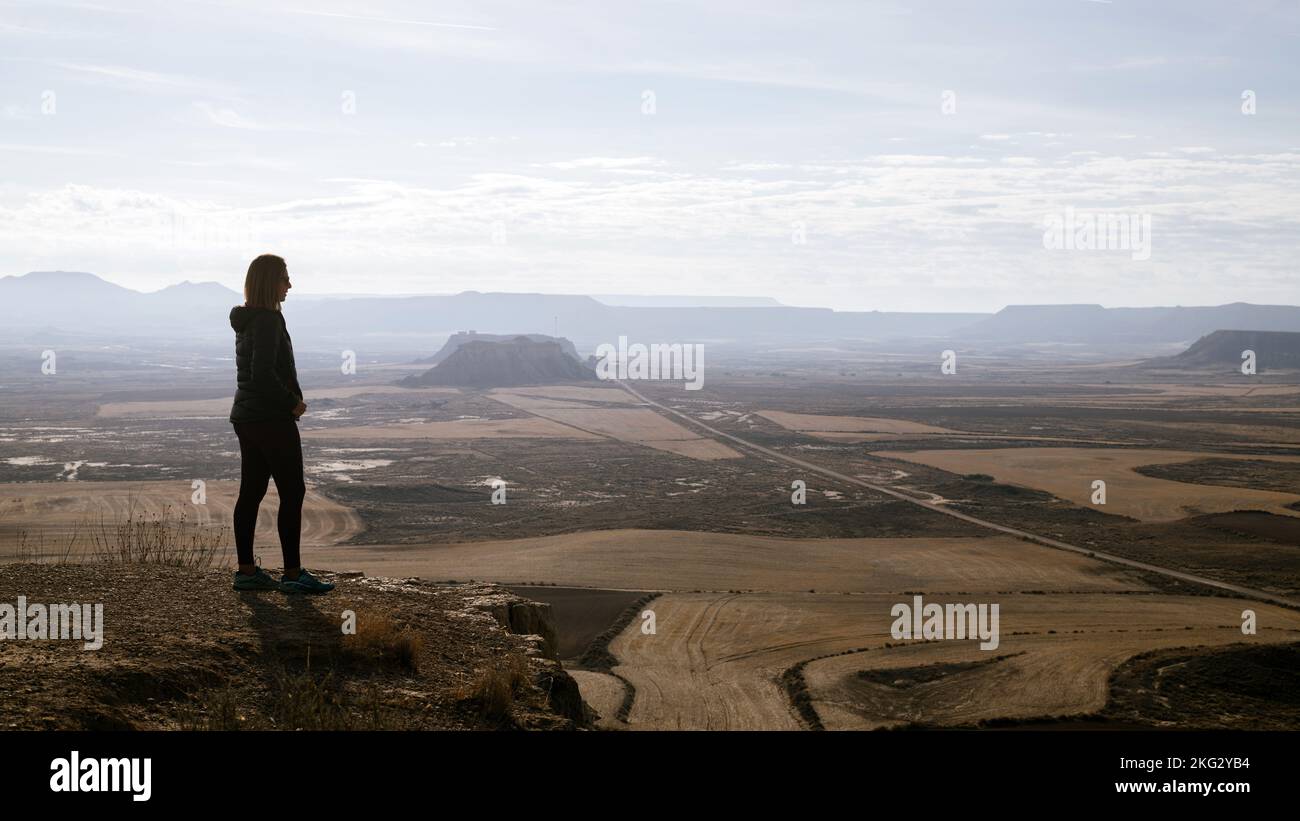 Silhouette d'une femme en profil observant la plaine aride du désert depuis le sommet. Désert avec des montagnes ravins et des plateaux en grès. Banque D'Images