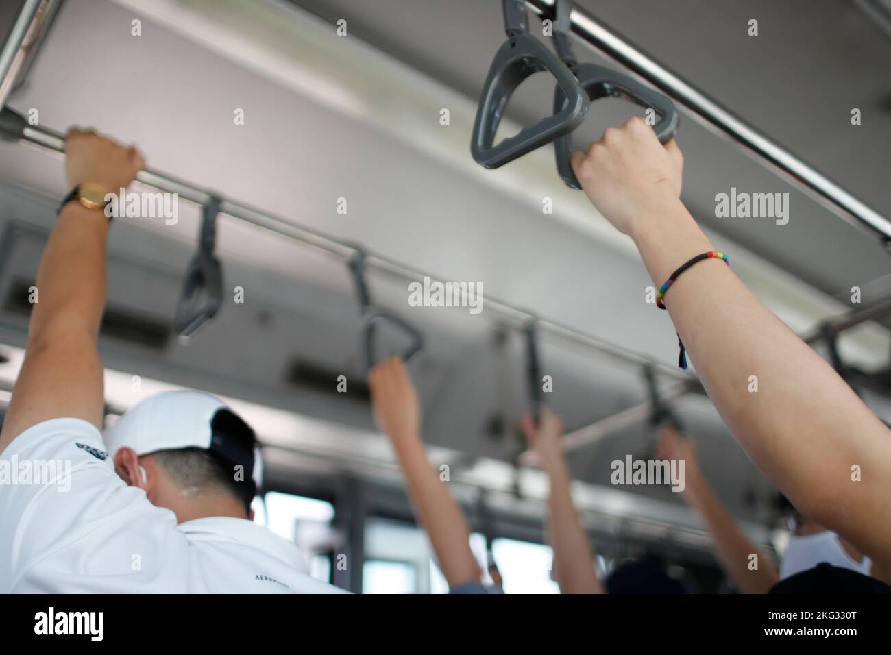 Mains tenant la poignée en tram, train, bus ou métro. Passager debout dans les transports en commun. Personne qui se déplace. Le transport va travailler. Hoi an. Banque D'Images