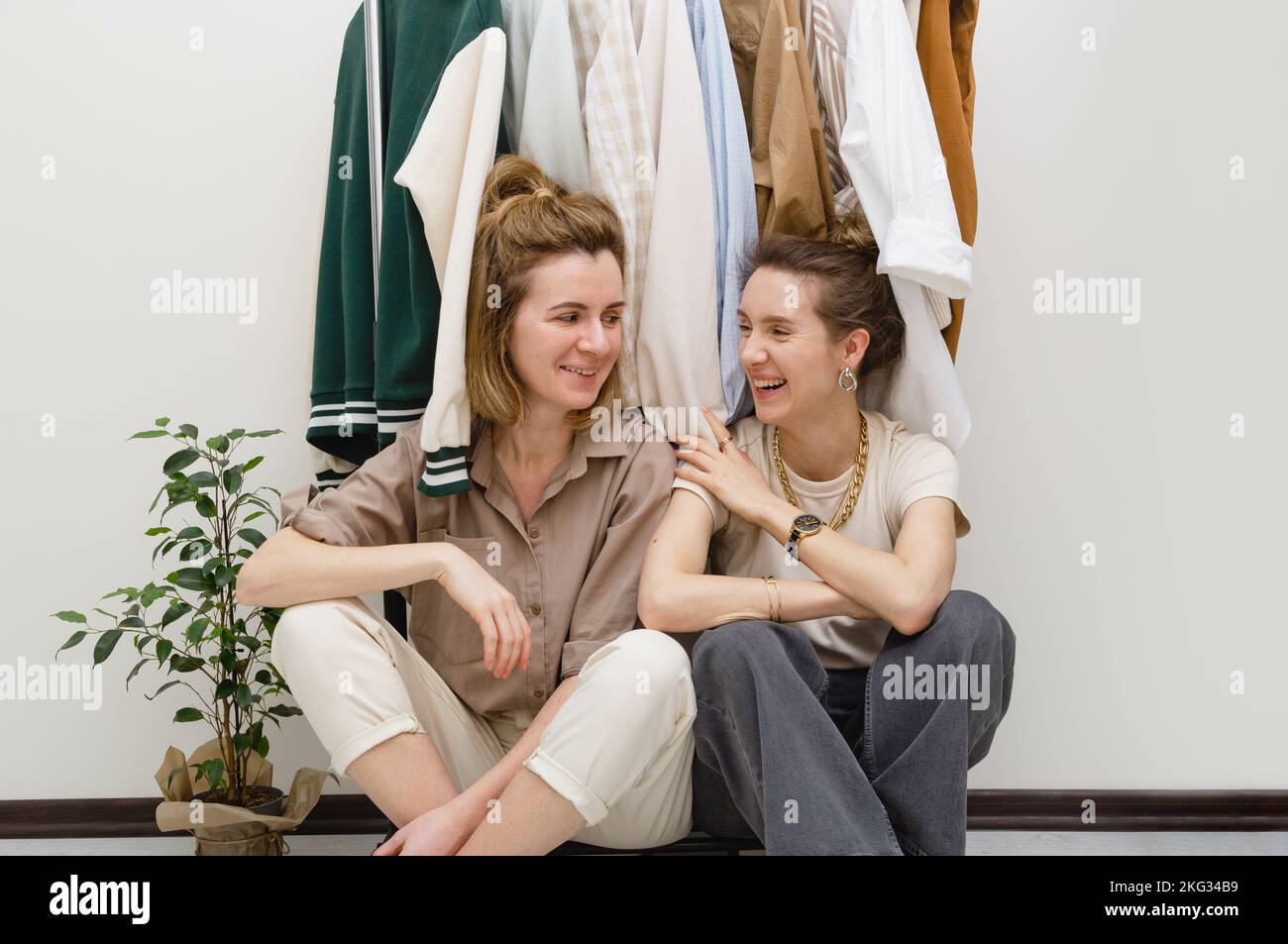 Concept d'organisation de garde-robe - deux amies de sexe féminin assis sous un porte-vêtements. Banque D'Images