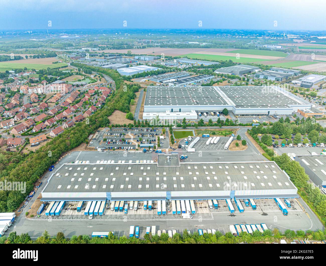 Tir de drone d'une zone immobilière avec verdure et de nombreux camions garés dans la baie de chargement Banque D'Images