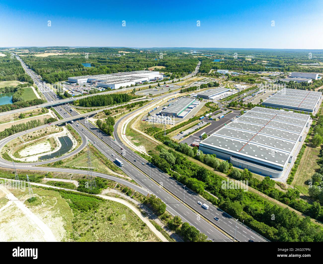 Tir de drone de la route développée du pont double de l'autoroute entourée d'une zone commerciale et d'une végétation luxuriante Banque D'Images