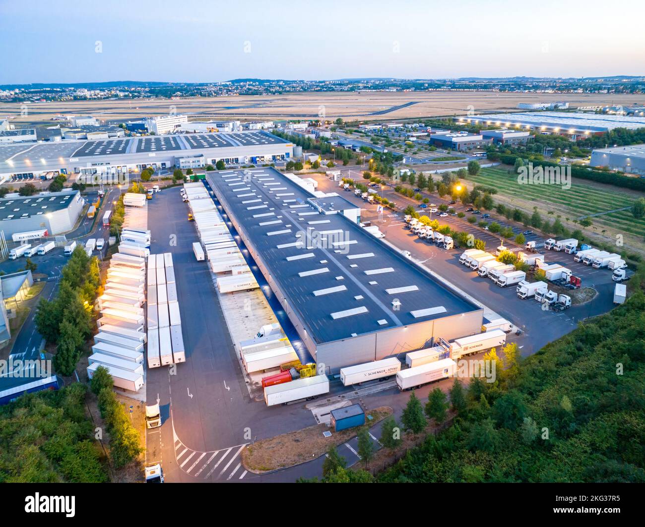 Vue aérienne des bâtiments d'entrepôt avec des camions garés dans la baie de chargement entourée d'une végétation luxuriante Banque D'Images