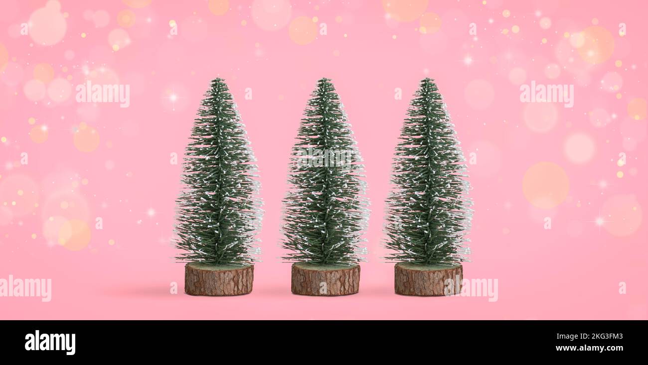 Petits arbres de Noël décoratifs sur fond de bokeh rose. Banque D'Images