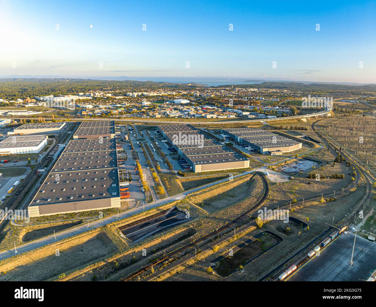 Un tir de drone sur les toits des usines au milieu du matin et de nombreux camions avec semi-remorques chargent des marchandises dans le Grans, en France Banque D'Images