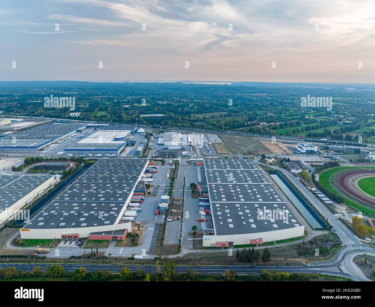 Tir de drone de deux grands bâtiments d'entrepôt près de l'autoroute nationale à travers les propriétés immobilières commerciales nouvellement développés entouré de verdure luxuriante Banque D'Images