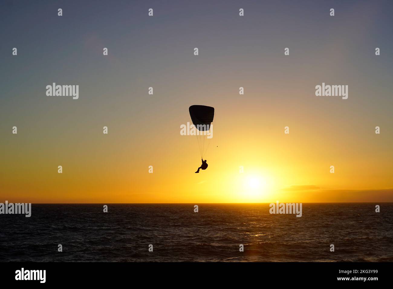 Silhouette d'un parapente au coucher du soleil, sur la plage Banque D'Images