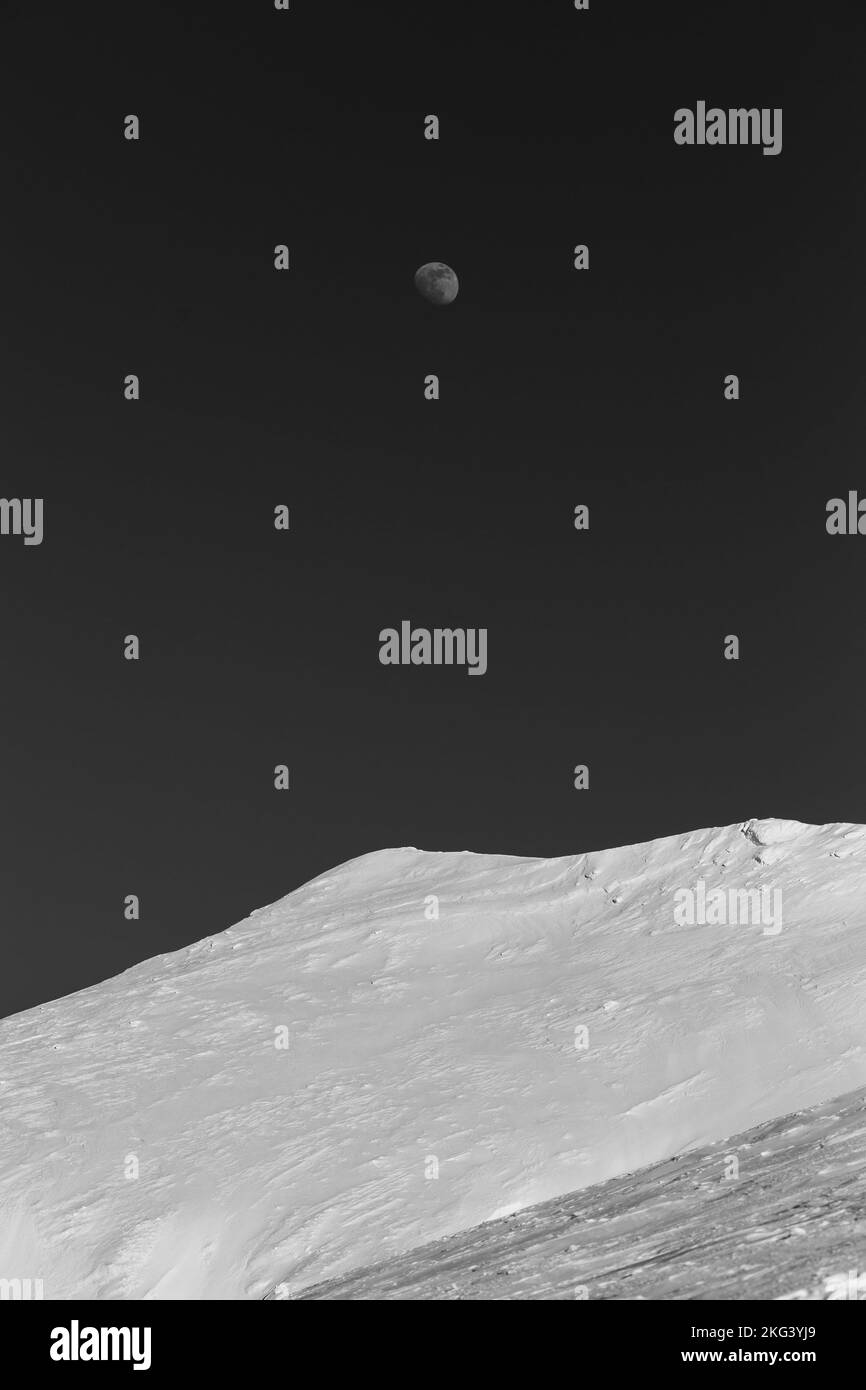 Sommet de montagne recouvert de neige avec la lune en arrière-plan Banque D'Images