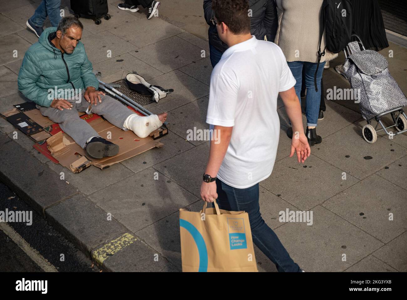 Homme sans abri portant une jambe moulée sur un trottoir de Londres Banque D'Images