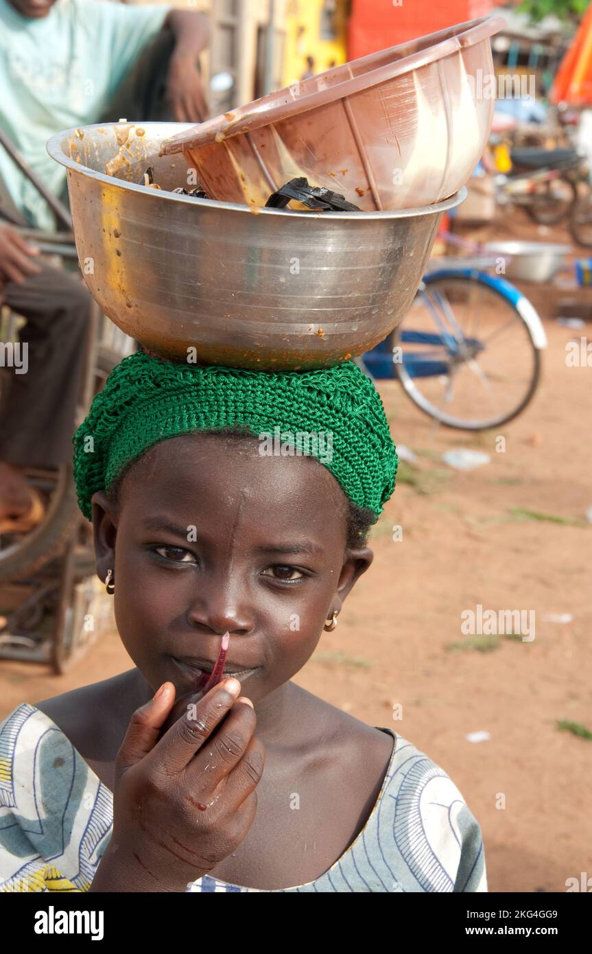 Fille portant des bols sur la tête, Natitingou, Atacora, Bénin. En Afrique, les filles apprennent à tout porter sur leur tête - très bon pour la posture. Banque D'Images