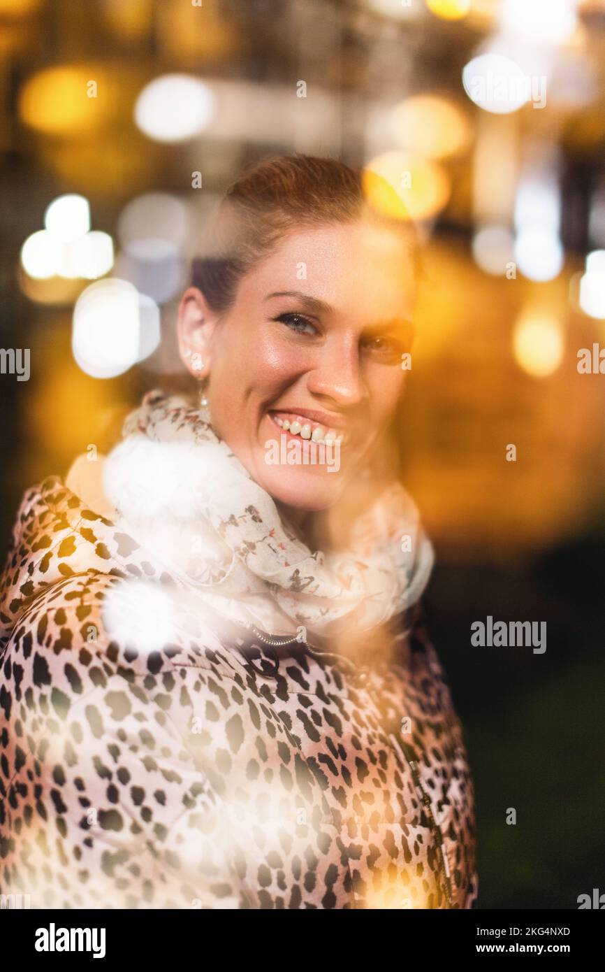 Bonne jeune femme urbaine à tête rouge en léopard pelage à l'hiver ville lumières un sourire crasseux la nuit, technique de double exposition Banque D'Images