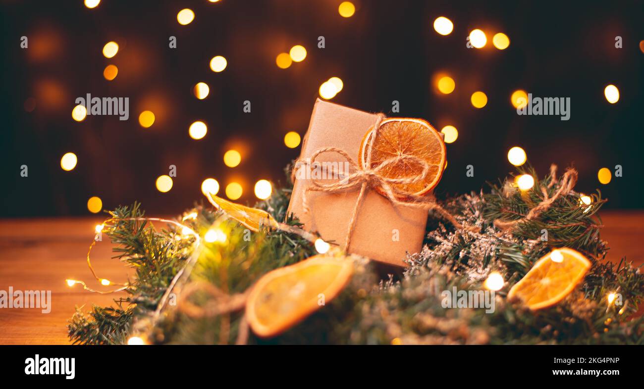 Boîte cadeau en carton Kraft attachée avec une corde de jute rugueuse sur fond de bois gris avec des branches d'arbre de Noël et des décorations de Noël Banque D'Images