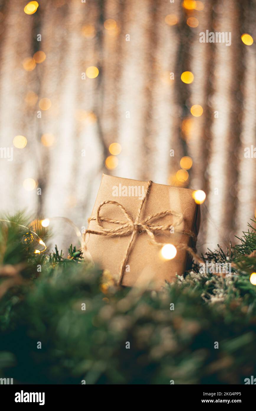 Boîte cadeau en carton Kraft attachée avec une corde de jute rugueuse sur fond de bois gris avec des branches d'arbre de Noël et des décorations de Noël Banque D'Images