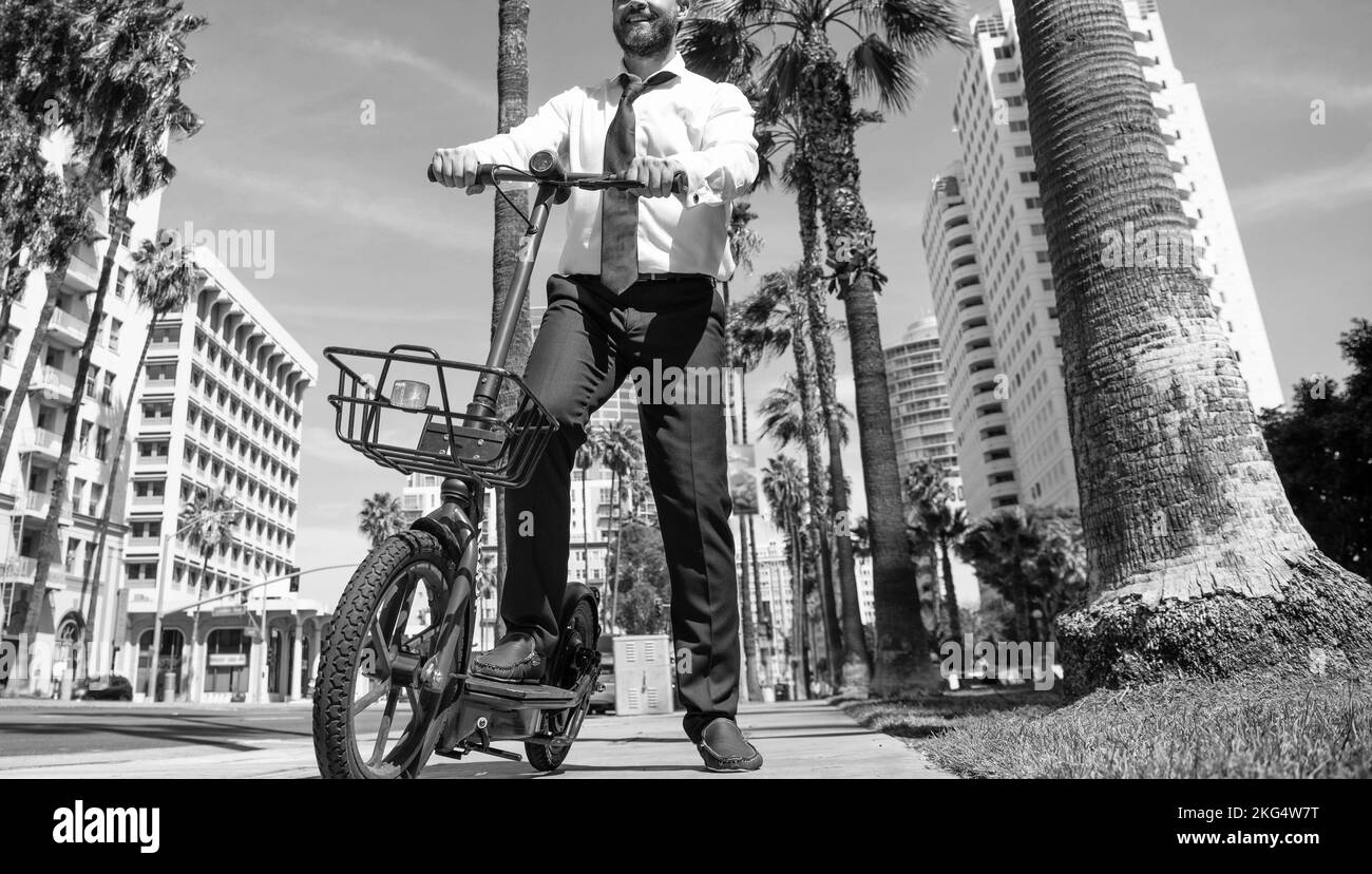 Happy Manager dans les vêtements de coffrage utiliser e-scooter dans la rue, le style de vie urbain Banque D'Images