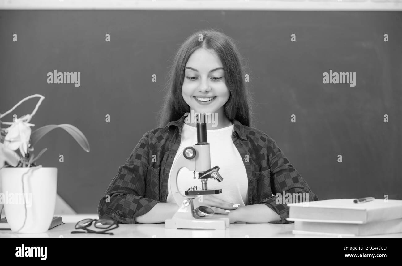 bonne jeune fille utilisant le microscope. retour à l'école. étudier la biologie, laboratoire de chimie Banque D'Images