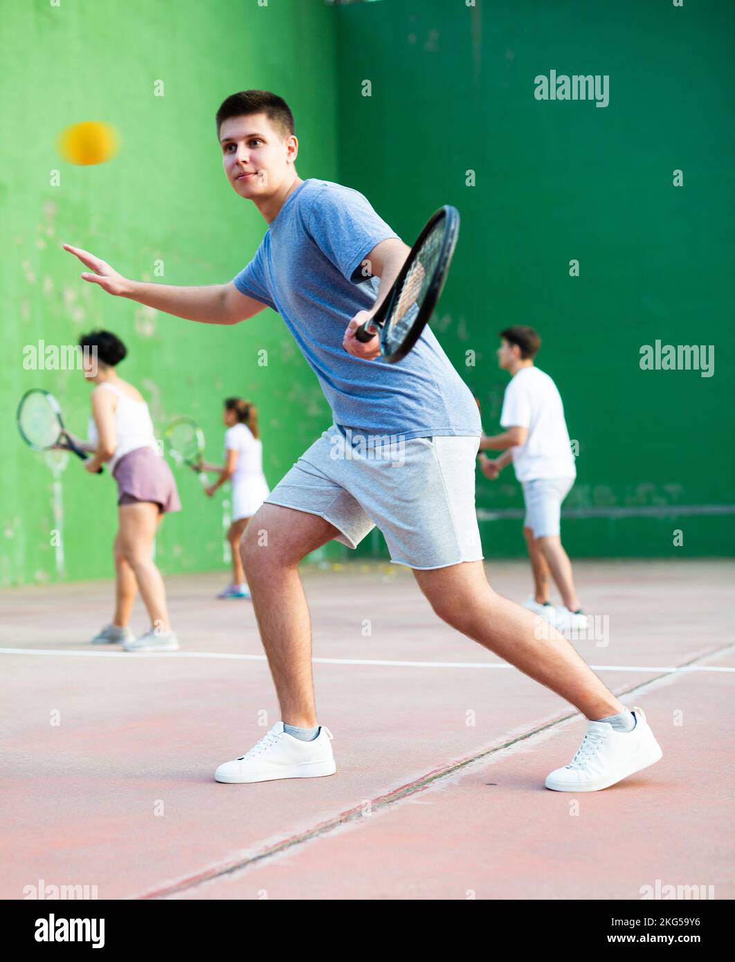 Jeune homme jouant frontenis sur un terrain de fronton en plein air en été Banque D'Images