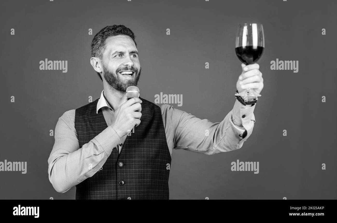 Happy man toastmaster lève un verre de vin pour proposer des toasts avant de boire un fond rouge, des encouragements Banque D'Images