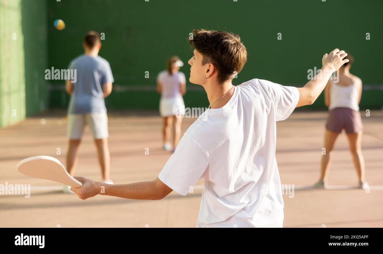 Adolescent caucasien dans des vêtements de sport jouant paleta fronton sur le terrain Banque D'Images