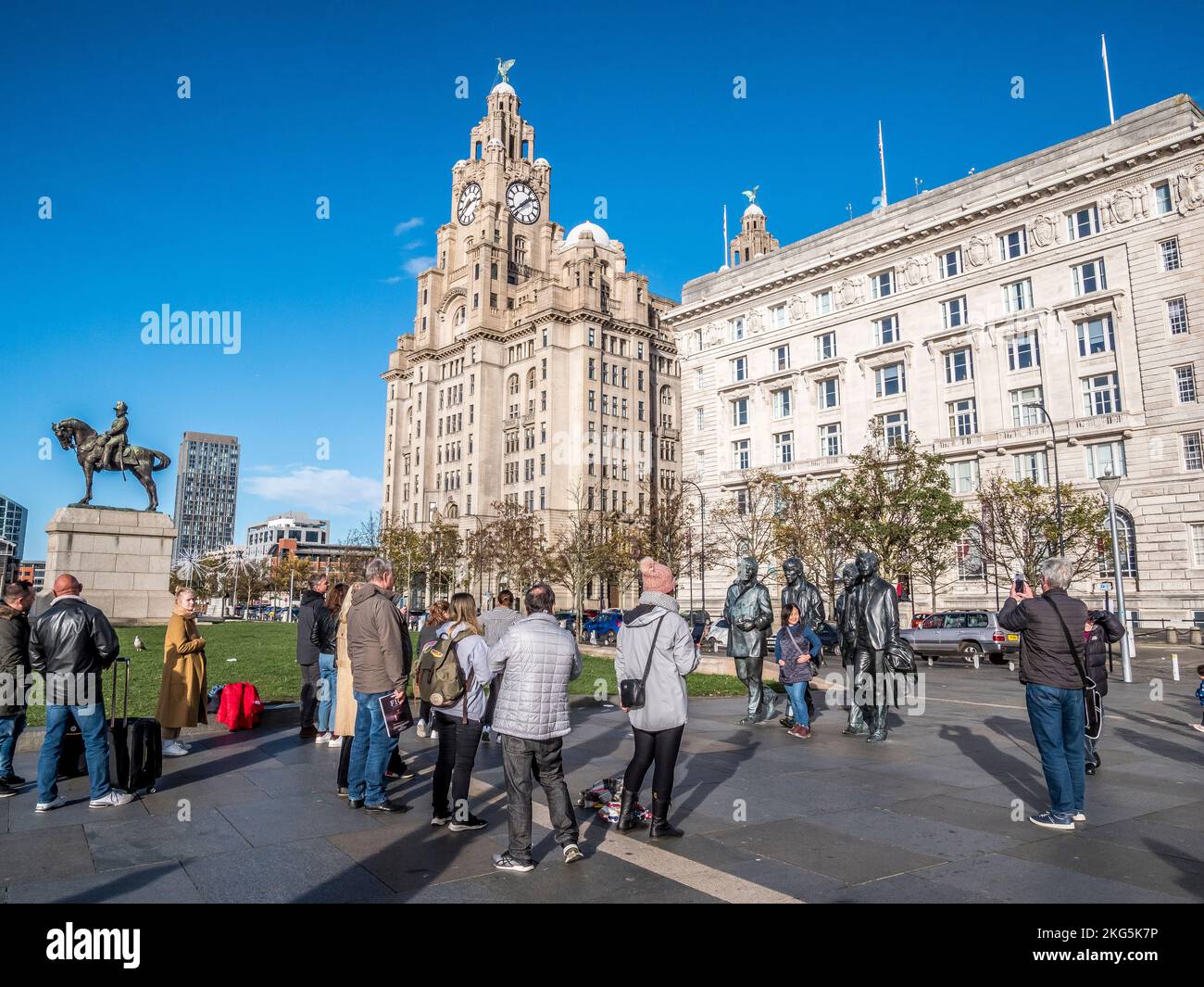 Scène de rue à Liverpool avec les touristes faisant la queue pour avoir des selfies avec les statues du célèbre groupe pop Beatles, ainsi que le bâtiment du foie Banque D'Images