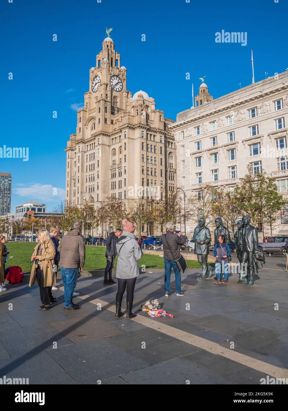 Scène de rue à Liverpool avec les touristes faisant la queue pour avoir des selfies avec les statues du célèbre groupe pop Beatles, ainsi que le bâtiment du foie Banque D'Images