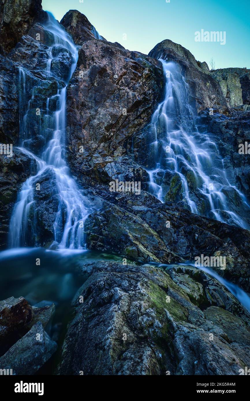 Belle cascade avec effet eau floue. Photo prise dans la vallée des cinq étangs dans les montagnes polonaises des Tatras. Photo à exposition longue. Banque D'Images