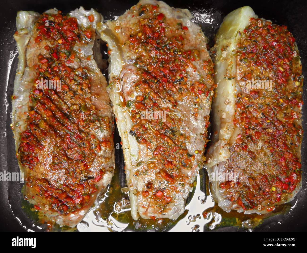 Trois steaks de bœuf rôtis aux épices dans une casserole. Banque D'Images