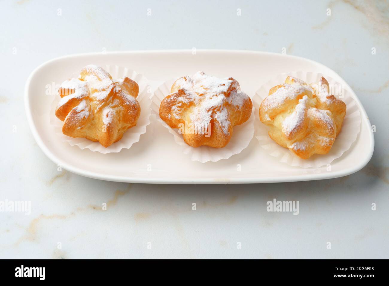 Profiteroles maison avec sucre en poudre sur plaque blanche Banque D'Images