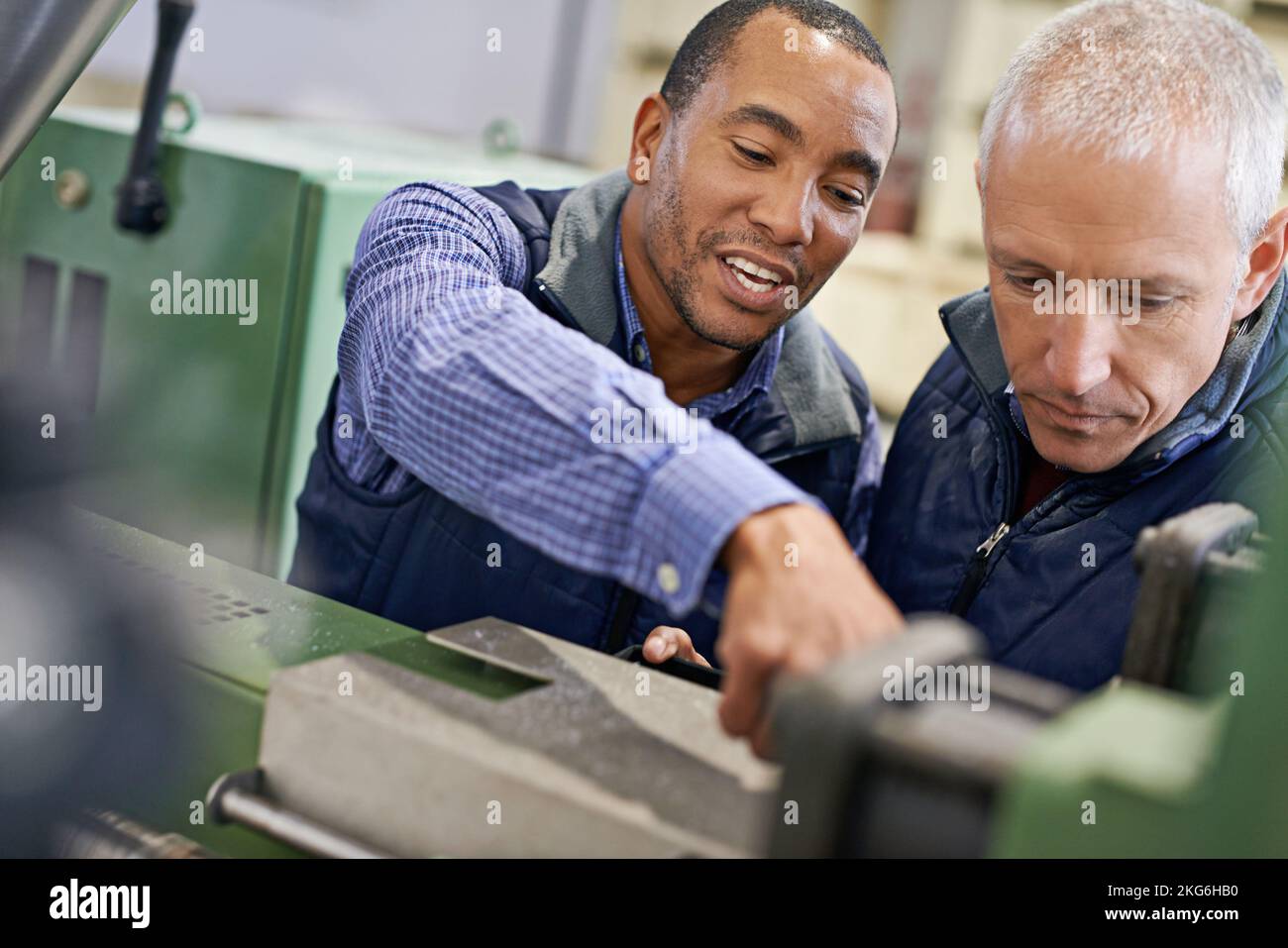 Ceci nécessite un réglage. deux hommes travaillant sur les machines d'usine. Banque D'Images