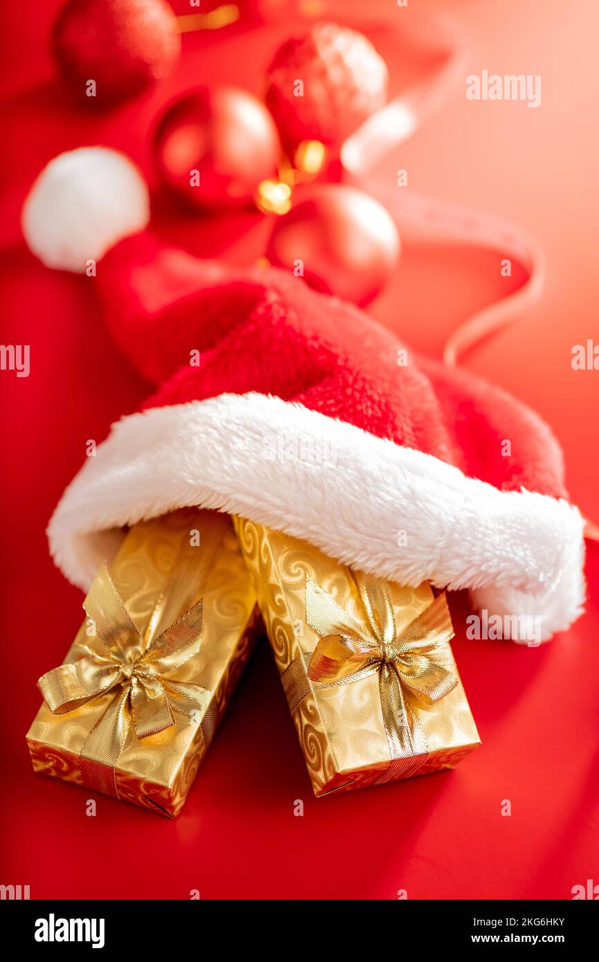 Cadeau de noël doré en chapeau de père Noël rouge sur fond rouge. Banque D'Images