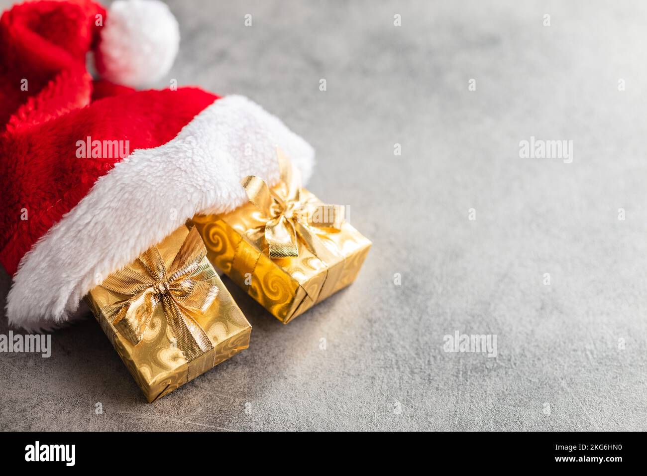 Cadeau de noël doré dans le chapeau de père Noël rouge. Banque D'Images