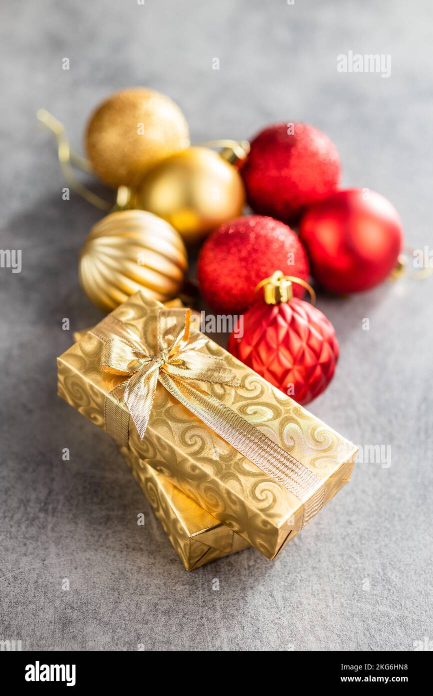Deux cadeaux de noël en or et des boules de noël sur la table grise. Banque D'Images