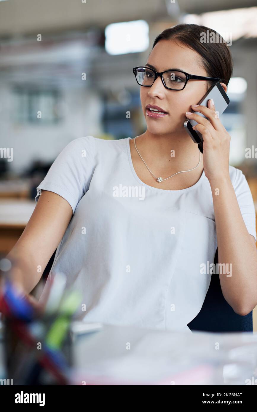 Profondément dans les négociations. une jeune femme d'affaires assise à son bureau parlant au téléphone. Banque D'Images
