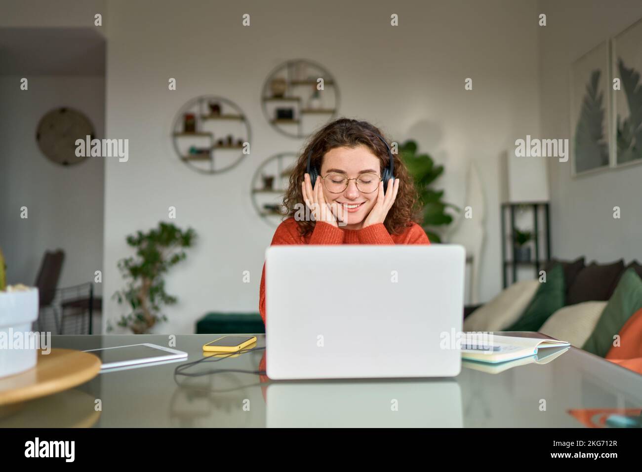 Jeune femme souriante dans un casque écoutant de la musique podcast apprendre à la maison. Banque D'Images
