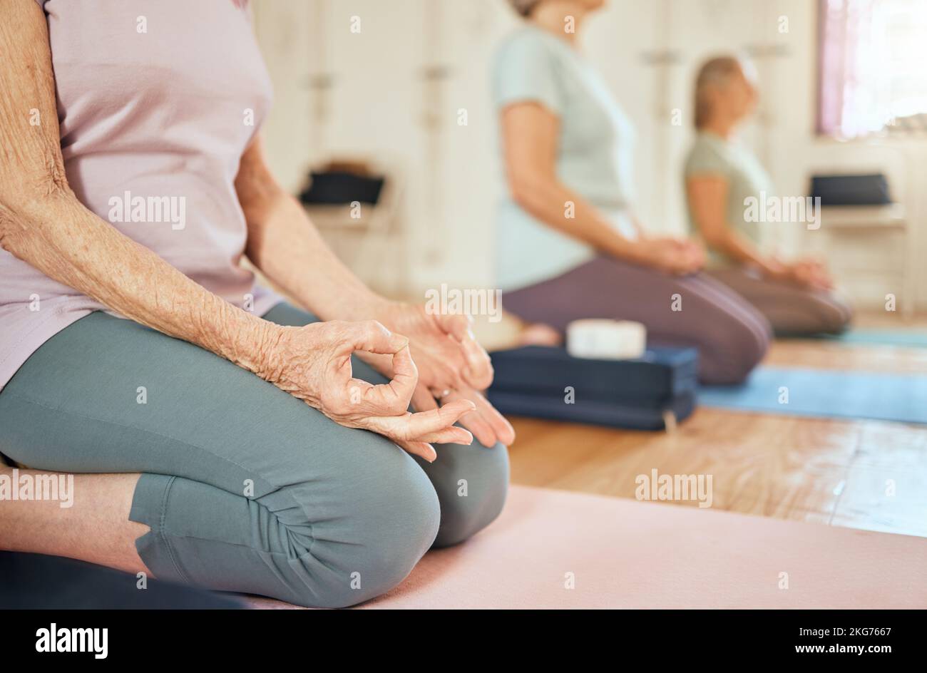 Yoga, mains de lotus et femmes âgées en salle de gym méditant pour le chakra et la santé spirituelle. Zen, méditation et groupe de femmes âgées à la retraite formation à Banque D'Images