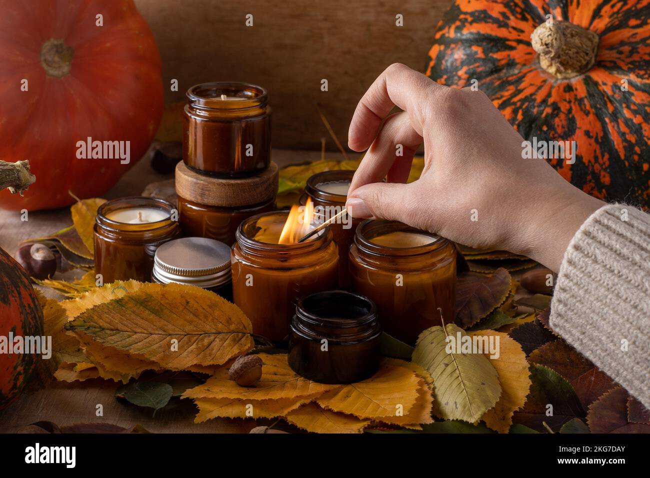 les bougies de soja légères brûlent dans des pots en verre. Feuilles d'arbre, citrouille. Confort à la maison. Bougie dans un pot brun. Parfum et lumière. Bougie parfumée faite à la main. Aromathérapie. Ambiance d'automne. Décoration chaleureuse à l'automne. Banque D'Images