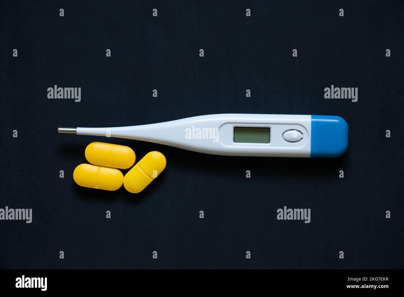 le thermomètre électronique se trouve à côté des pilules jaunes sur un fond isolé, la médecine et la pharmacie, la santé et le traitement, les pilules et les antibiotiques Banque D'Images