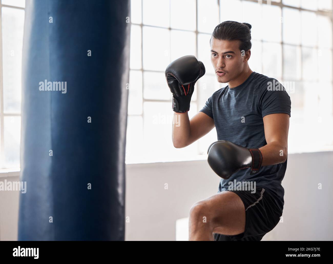 Fitness, boxe et entraînement d'homme pour une compétition de combat, d'entraînement ou de match avec un sac de boxe dans la salle de gym. Sport, motivation et athlète boxer faire Banque D'Images