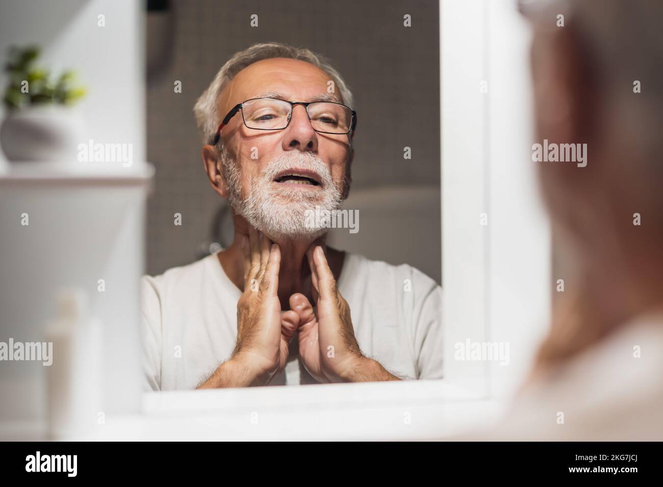 Un homme âgé applique une lotion après le rasage après la tonte de la barbe. Banque D'Images