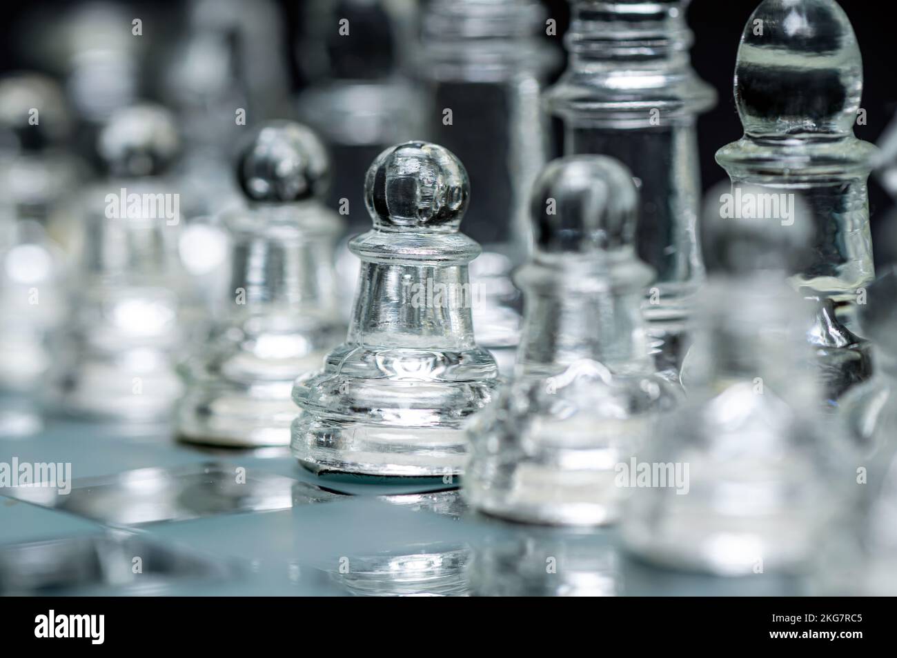 verre transparent, pièces d'échecs transparentes sur un damier, mise au point sélective, gros plan, isolé sur le noir Banque D'Images
