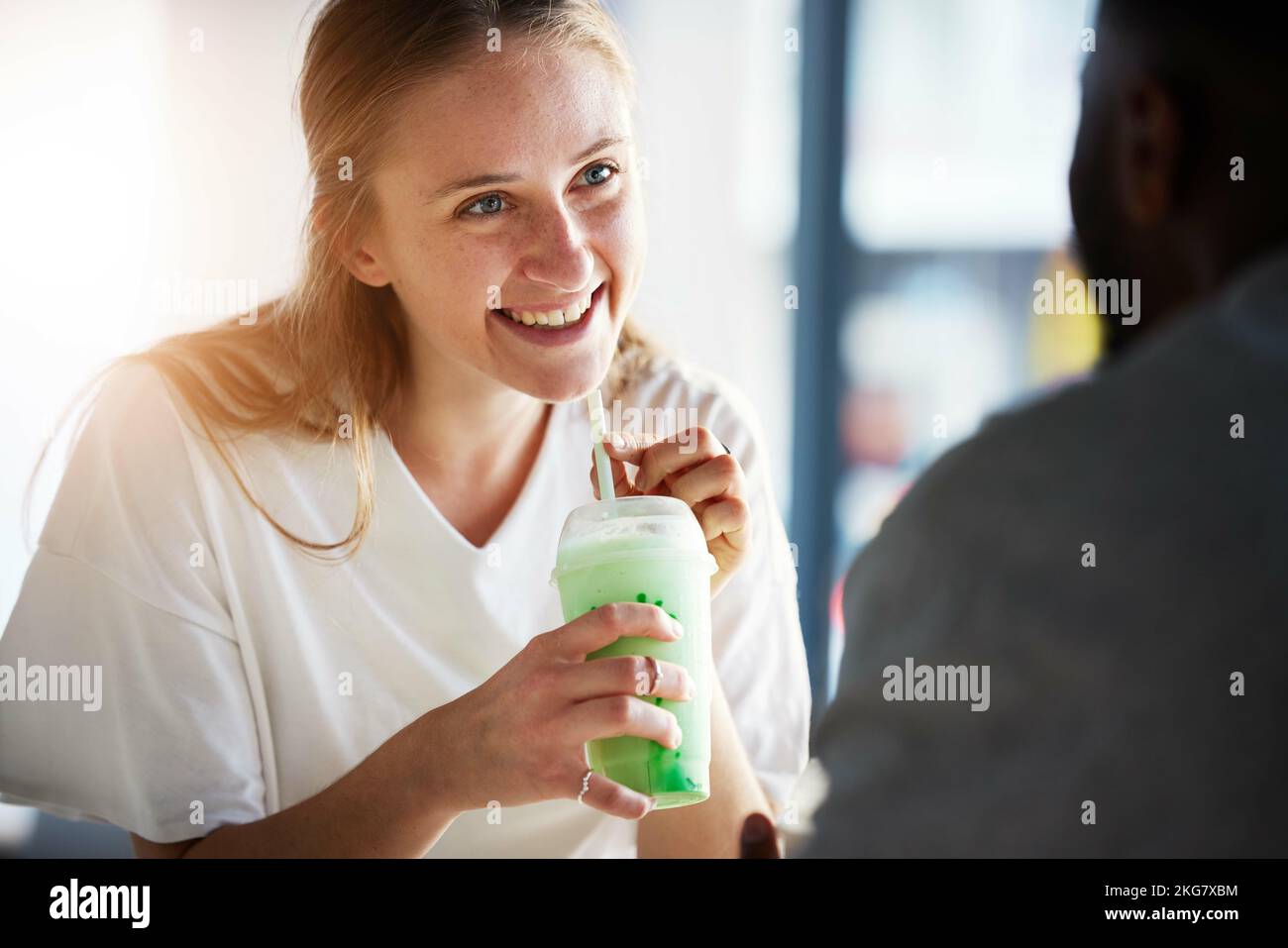 Femme, sourire et smoothie le jour au restaurant avec l'homme en relation interraciale, amour et soin. Fille, heureux et boire milkshake pour la santé Banque D'Images