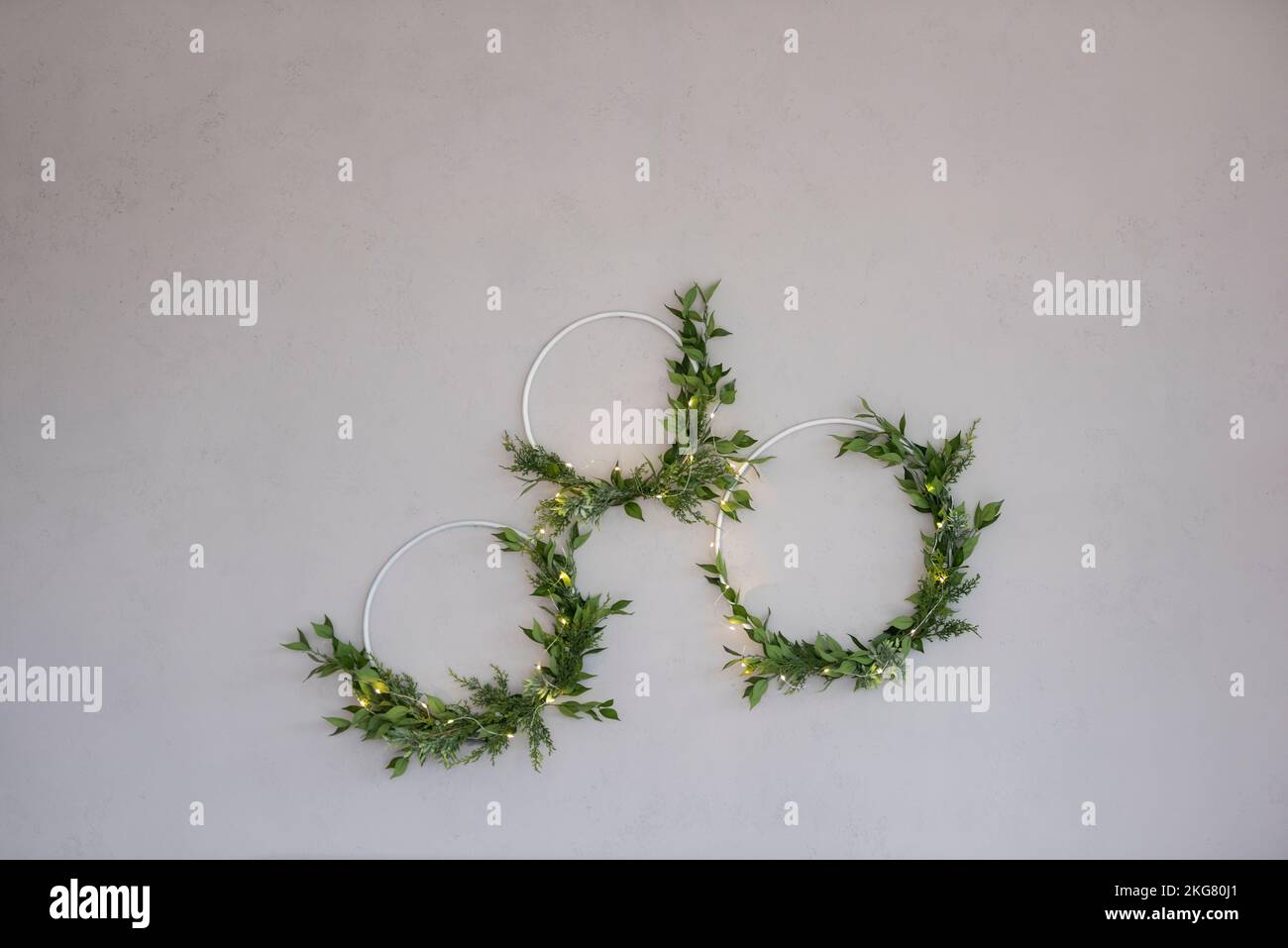 Sur un mur en béton gris, il y a trois couronnes laconique, élégantes et vertes en matériaux naturels. Guirlande festive. Décoration intérieure minimaliste rouille Banque D'Images