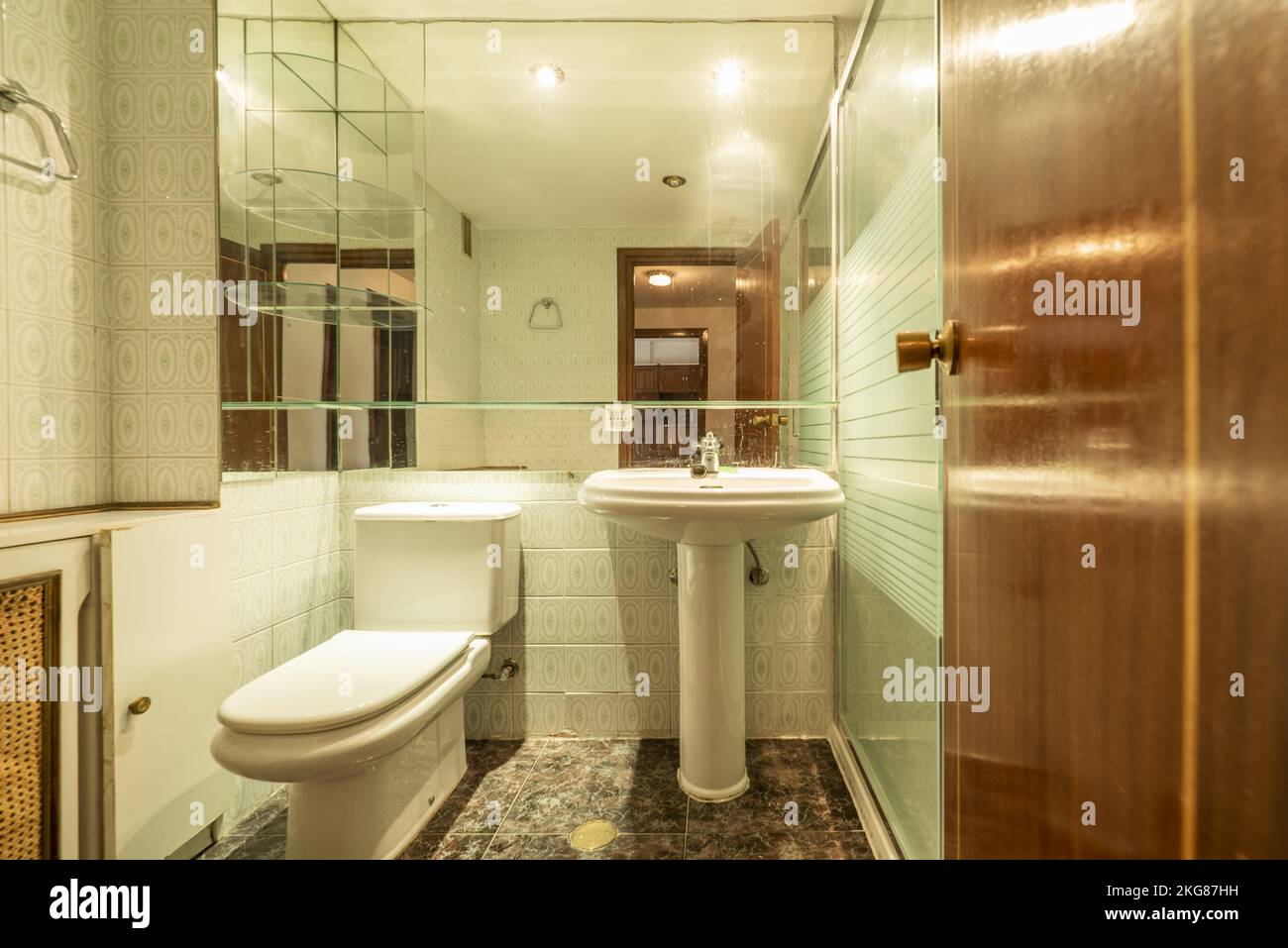 Petite salle de bains avec lavabo en porcelaine sur pied, grand miroir sur le mur et vieux carreaux Banque D'Images