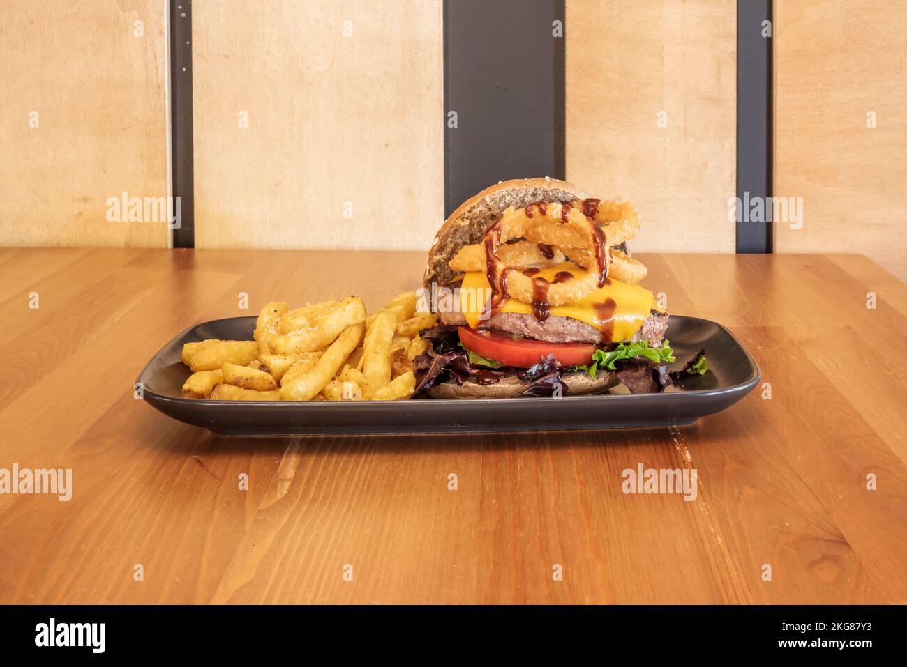 Hamburger avec de nombreuses garnitures avec sauces et frites maison Banque D'Images