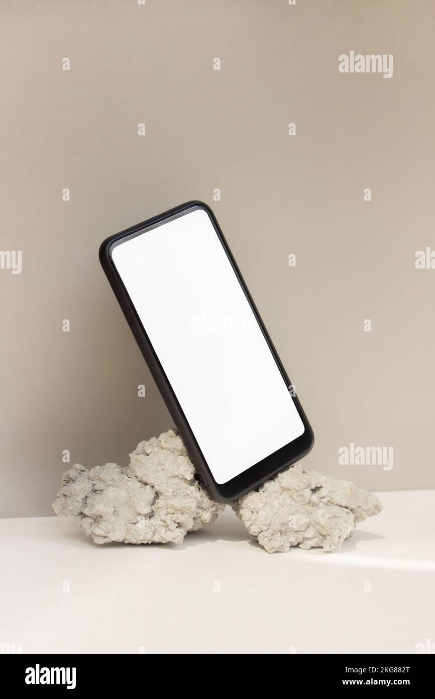 Maquette smartphone équilibre sur pierre naturelle sur fond beige. Téléphone avec modèle d'écran vierge Banque D'Images