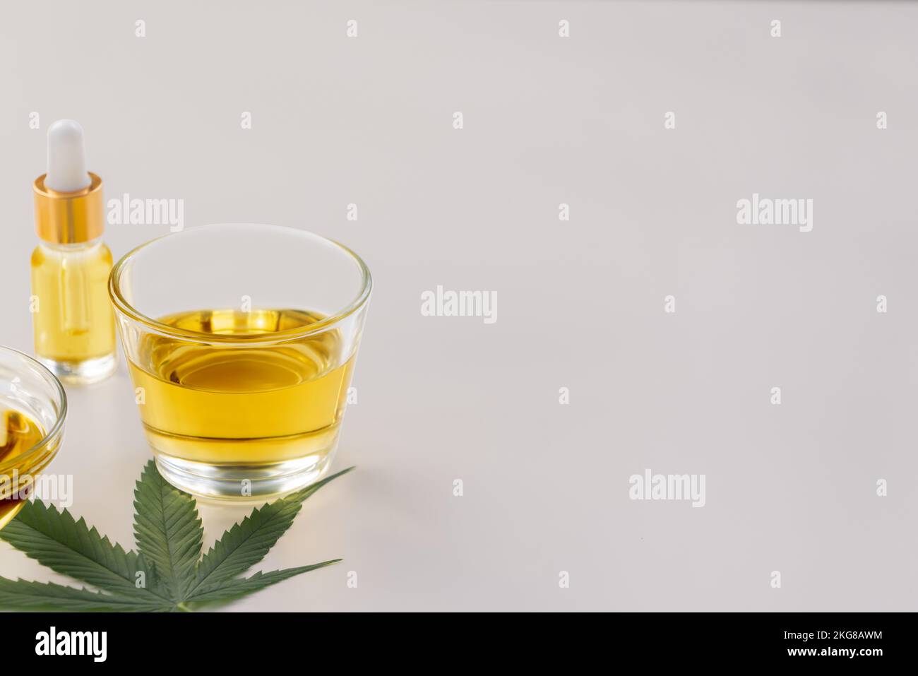 Un bol en verre d'huile de CBD, un bourgeon de cannabis et une feuille de chanvre sont présentés sur fond blanc. Conception de l'extrait d'huile légalisé du cannabis. Banque D'Images
