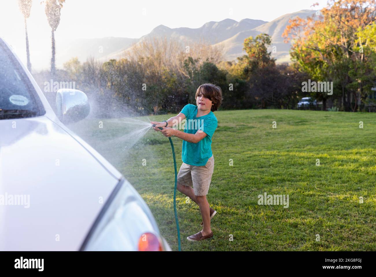 Afrique du Sud, Stanford, Boy (8-9) lavage SUV sur grande pelouse verte Banque D'Images