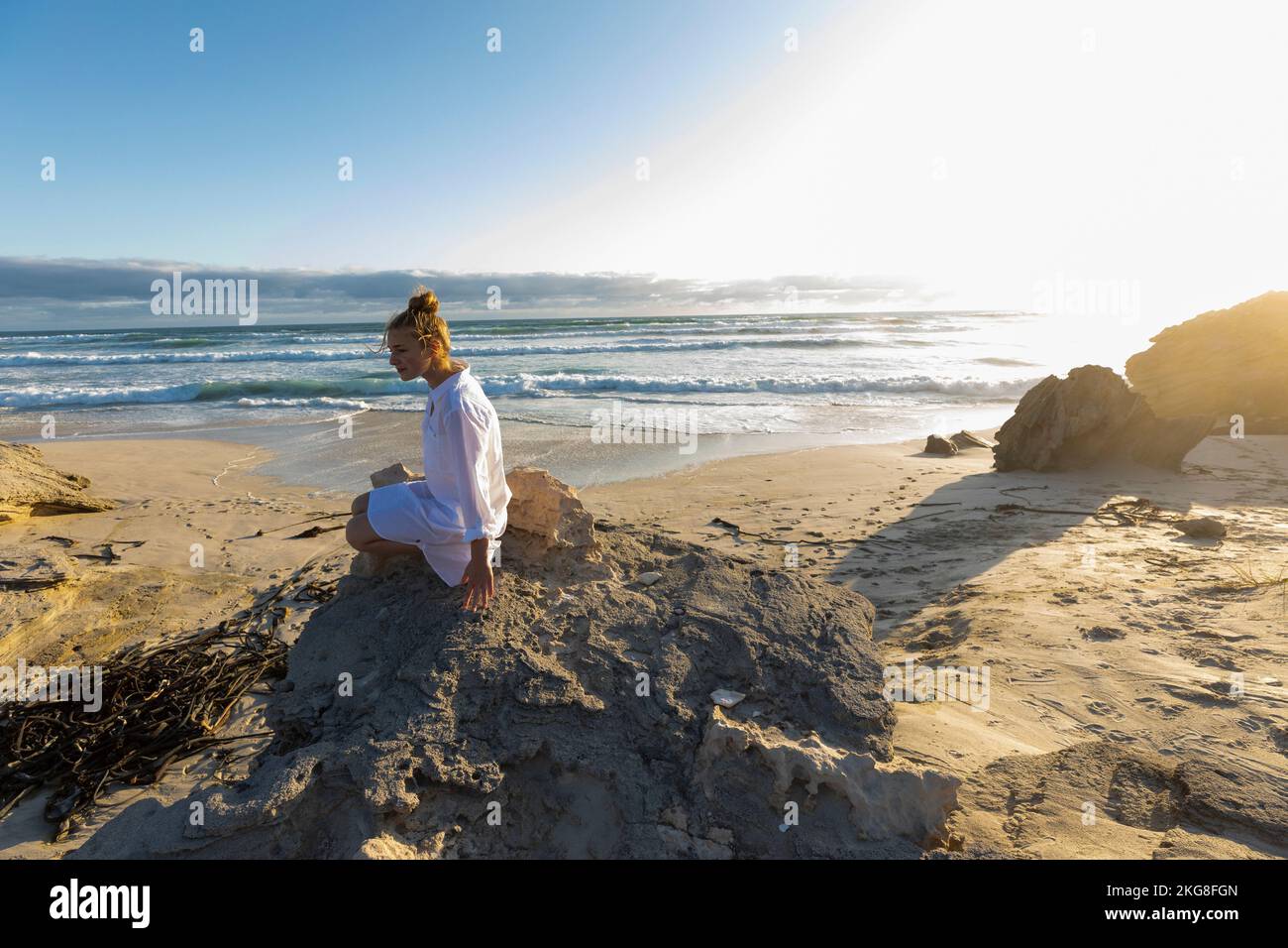 Afrique du Sud, Hermanus, adolescente (16-17) assise sur des rochers sur la plage Banque D'Images