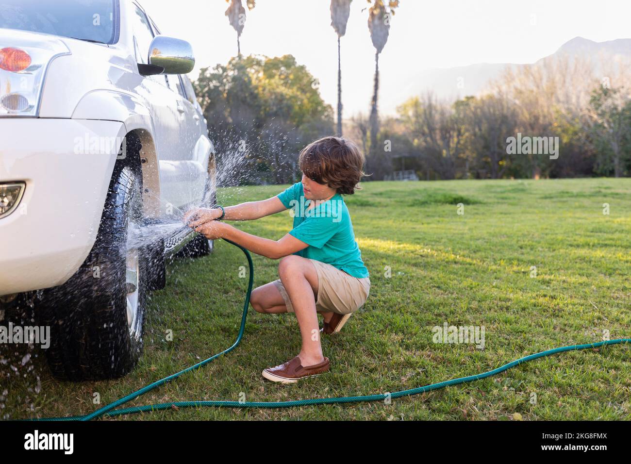Afrique du Sud, Stanford, Boy (8-9) roue de lavage de SUV sur pelouse verte Banque D'Images