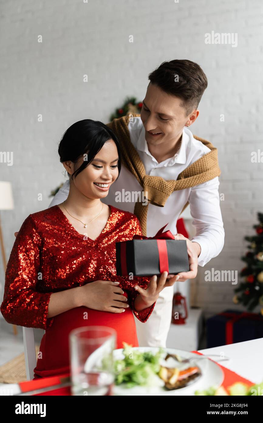 Jeune mari cadeau de Noël à une femme asiatique enceinte et élégante Banque D'Images