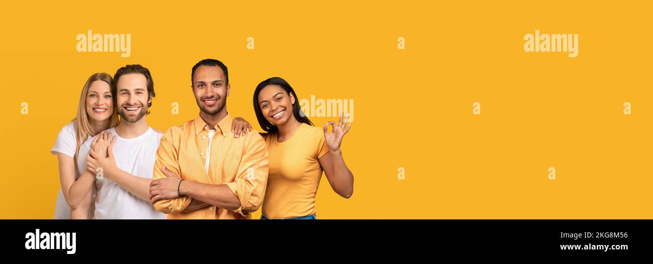 Heureux jeunes couples blancs et noirs posant sur le jaune Banque D'Images